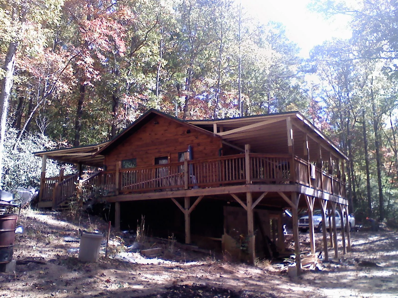 Log cabin with a wraparound porch and metal roof in the fall in Crescent